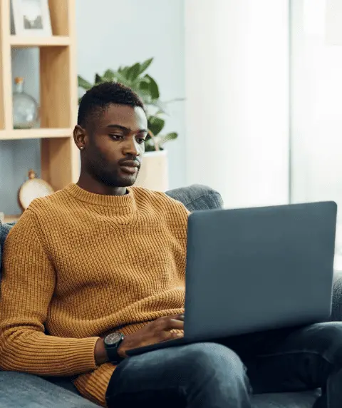 Young man sitting on a sofa and working on a laptop at home